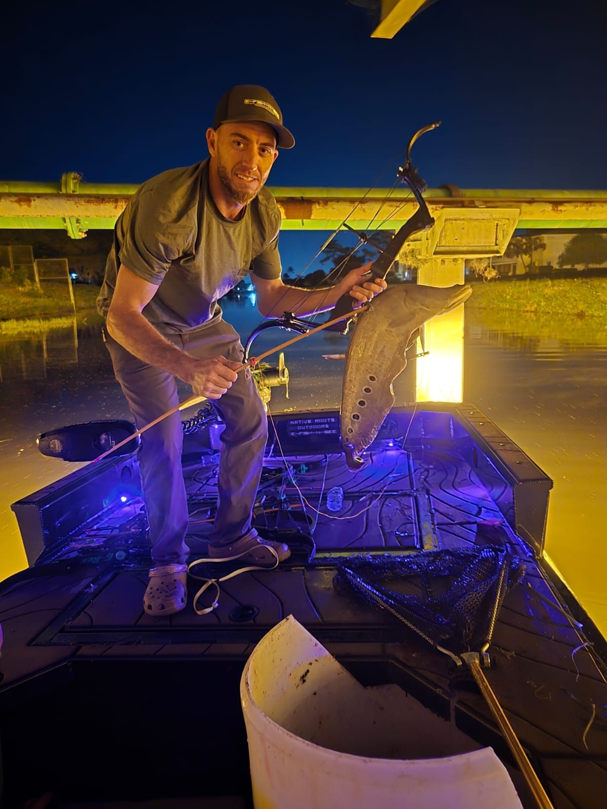 Native Roots guest holding a clown knife fish from the bowfishing deck