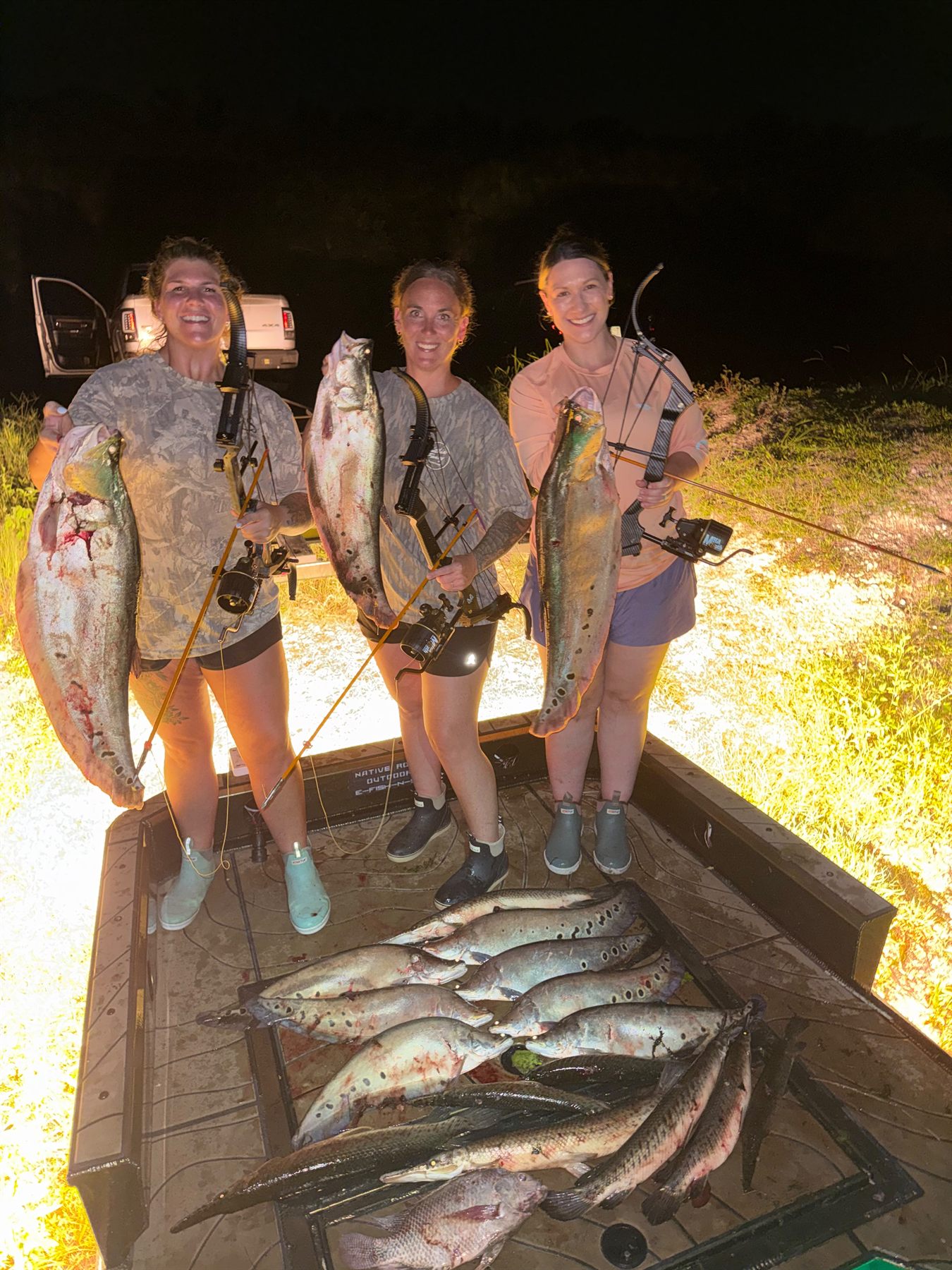 Three guests holding clown knife fish on a Native Roots bowfishing trip