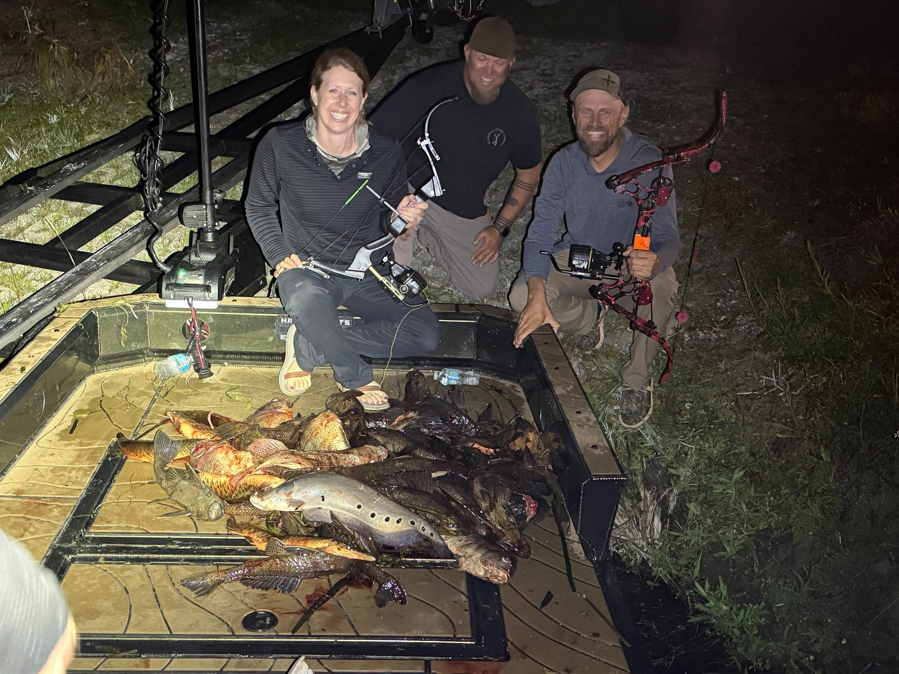 Native Roots guests smiling behind a full bowfishing catch on the boat deck